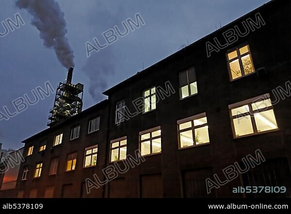 Office building with illuminated windows, smoking chimney, Sachtleben Chemie, Duisburg-Homberg, Ruhrgebiet region, North Rhine-Westphalia, Germany, Europe.