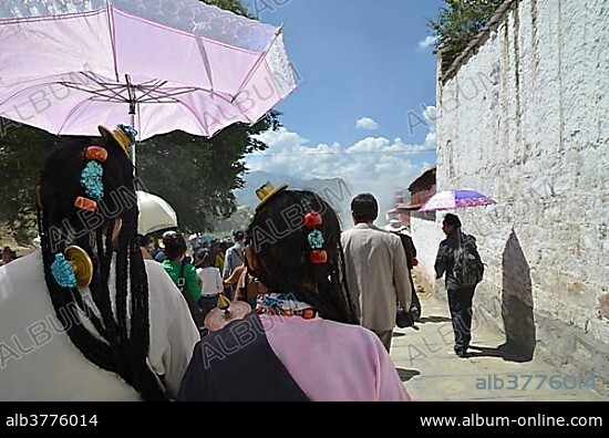 Tibetan Buddhism, Tibetan women with a traditional headdress and parasol at the revealing of the Buddha image, at the Shoton or Choedoen or Yoghurt Festival, Sera Monastery, Lhasa, Tibet, China, Asia.