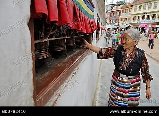 Pilgrim walking around stupa of Boudhanath and turning prayer wheel, Kathmandu, Nepal, Asia.