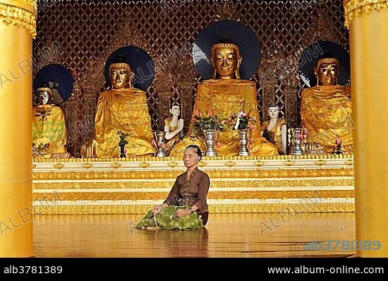 Woman meditating in front of Buddha statues, Shwedagon Pagoda, Yangon, Yangon Region, Myanmar, Burma, Asia.