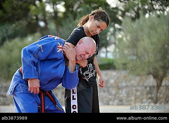 Student keeps her martial arts instructor in a headlock during a training session in a park.