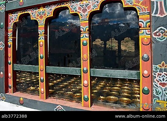 Lit butter lamps seen through a window, Tango Monastery, Bhutan, Asia.