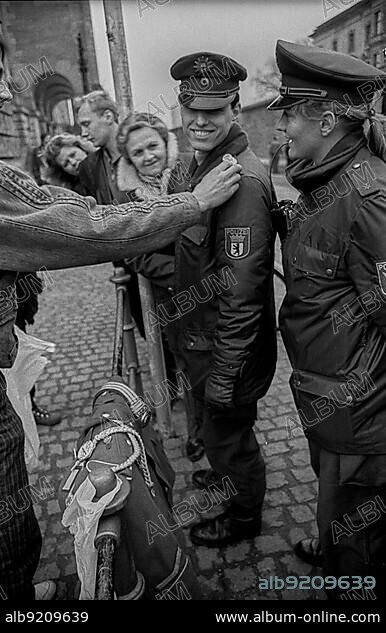 GDR, Berlin, 11.01.1990, West Berlin policemen on the market: gets a NVA shoulder piece..., at the Reichstag.