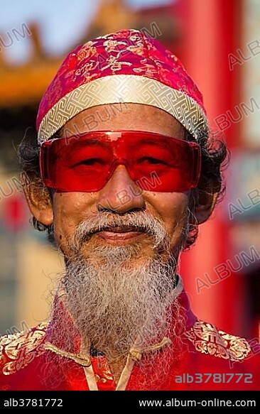 Portrait, old chinese man with red glasses, hat and beard, Chinese New Year, Spring Festival, Chinatown, Bangkok, Thailand, Asia.