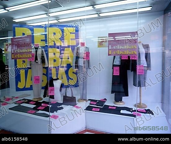 ESCAPARATE DE UNA TIENDA DE ROPA EN REBAJAS CON LOS PRECIOS EN EUROS Y EN PESETAS.