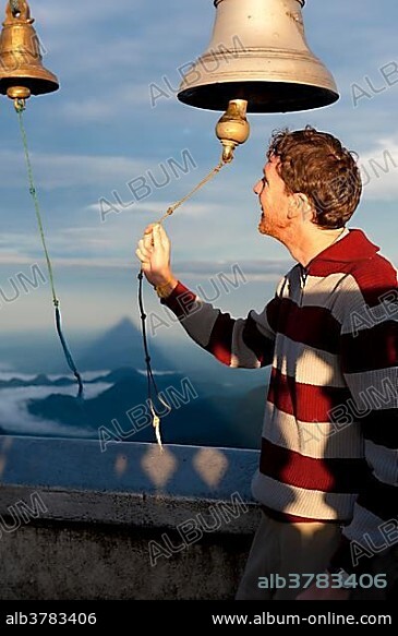 Man ringing a bell at a Buddhist temple, Adam's Peak, Sri Pada, Dalhousie, Zentrales Hochland, Sri Lanka, Asia.