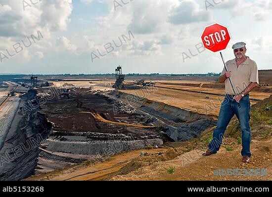 Man standing on the edge of an open pit, holding up a stop sign, Grevenbroich, North Rhine-Westphalia, Germany, Europe.