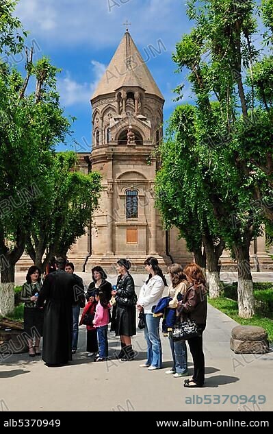 Armenian orthodox priest, monk discussing with people, with main cathedral at Echmiadzin, Unesco World Heritage Site, Armenia, Asia.
