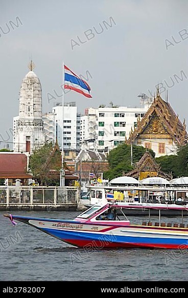 Boat on the Mae Nam Chao Phraya River, Thai national flag, in the back a Buddhist temple, Bangkok, Thailand, Southeast Asia, Asia.
