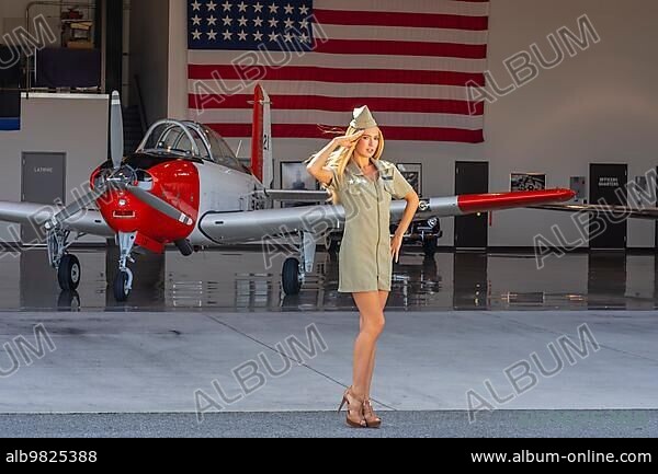 A beautiful blonde model poses with a vintage WWII aircraft.
