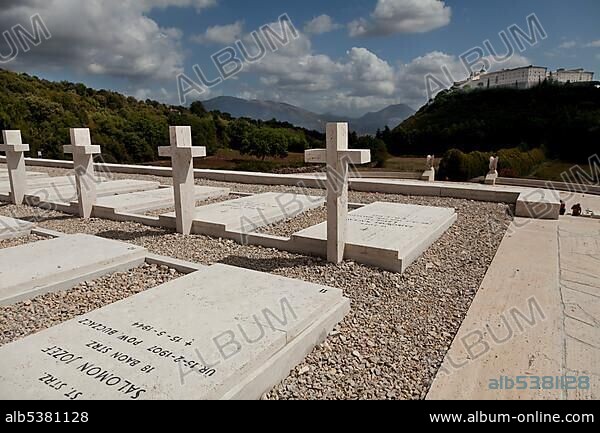 Gravestones on the Polish Cemetery and Monte Cassino Abbey on the mountain in the distance, Cassino, Lazio, Italy, Europe.