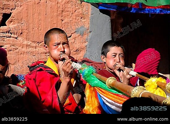 Tibetan monk and nun blow in trumpets Rongbuk Monastery Tibet China.