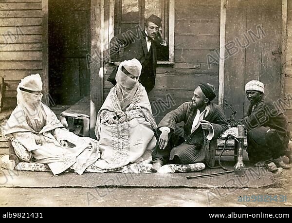 Turkish family in front of their home; woman are veiled; men with hookah; around 1870; Turkey; Historic; digitally restored reproduction from a 19th century original; Asia.