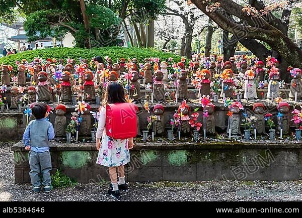 Two schoolchildren in front of Jizo statues with red caps, protective deities for deceased children, Unborn Children Garden. ZÅjÅji Temple, Buddhist Temple, Tokyo, Japan, Asia.