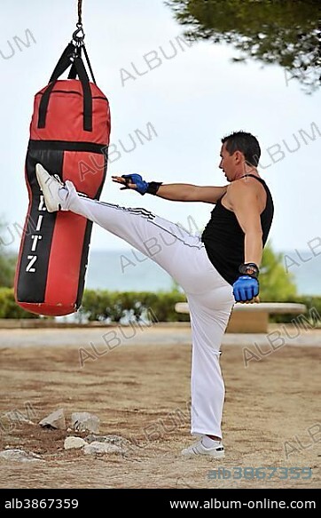 Man is kicking a sandbag during a training session.