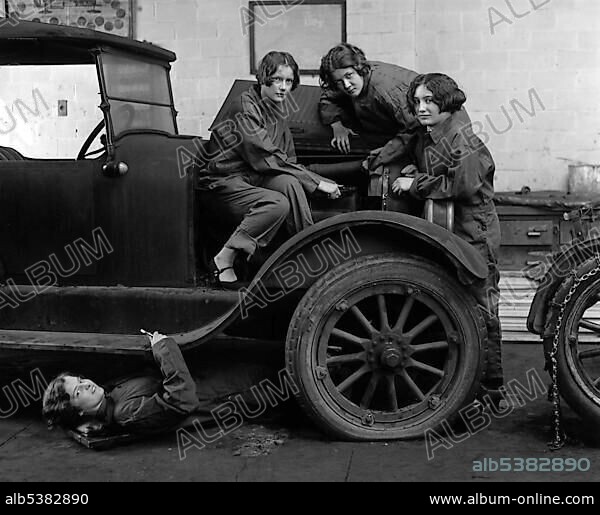 Female car mechanics fixing a car, historic picture from about 1920.