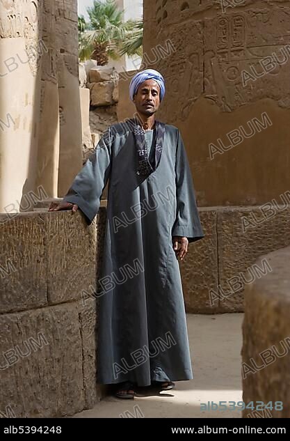 Nubian man wearing traditional clothing, standing between columns, Karnak Temple, Luxor, Egypt, Africa.