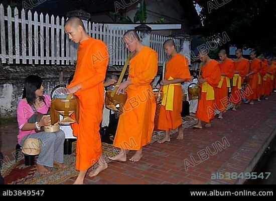 Buddhist monks with begging bowls receiving alms in the morning, Luang Prabang, Laos, Southeast Asia, Asia.