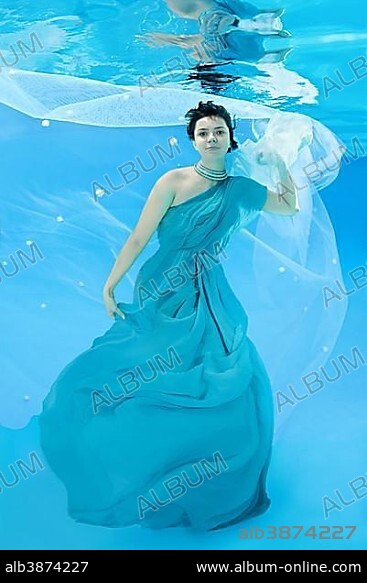 Young woman in long, blue dress poses under water.