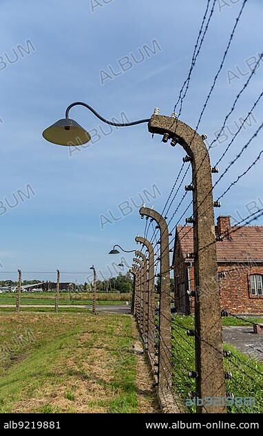 Auschwitz, Poland - 15 September, 2021: barbed wire fence and lanterns with guard house in the background at the Auschwitz concentration camp.