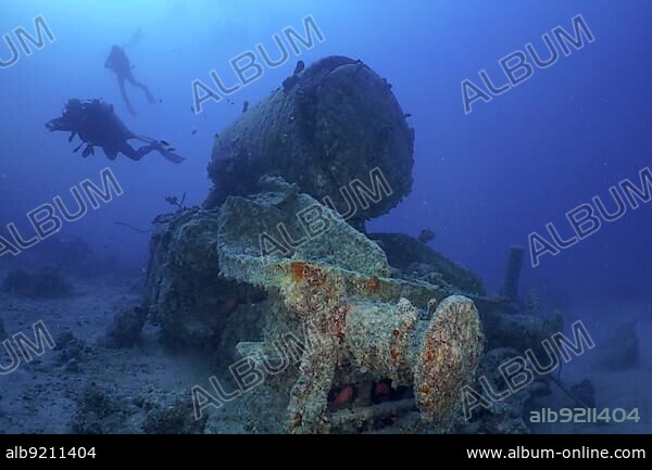 Remains of a steam locomotive from the Second World War on the seabed. Divers in the background. Dive site Thistlegorm wreck, Sinai, Egypt, Red Sea, Africa.