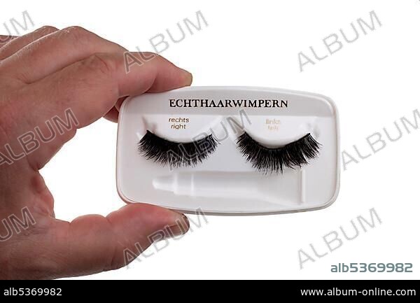 A man's hand holding an old pack of false eyelashes from the 60's.
