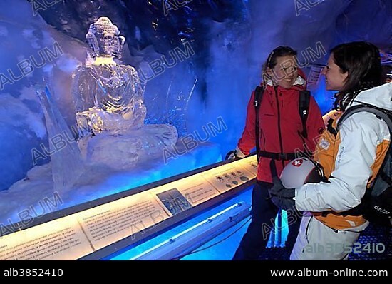 Ice Buddha statue admired by tourists in the ice cave in the Gletscherpalast or Glacier Palace, Klein Matterhorn Mountain, Zermatt, Valais or Wallis, Switzerland, Europe.