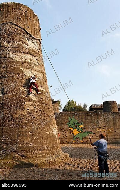 Little girl climbing up a concrete tower, climbing garden of the former steelworks of Thyssen at Meiderich, landscape park Duisburg-North, NRW, Germany, Europe.