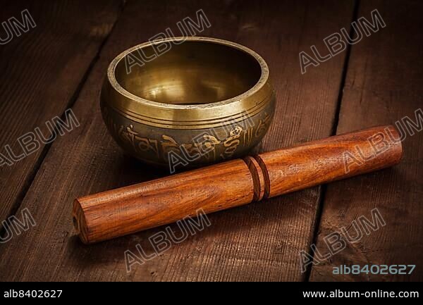 Tibetan buddhist singing bowl, rin gong, Himalayan bowl or suzu gong for meditation, music, relaxation, and personal well-being with mallet on wooden background.