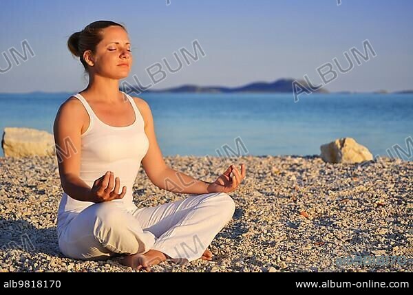 Young woman during yoga meditation on the beach.
