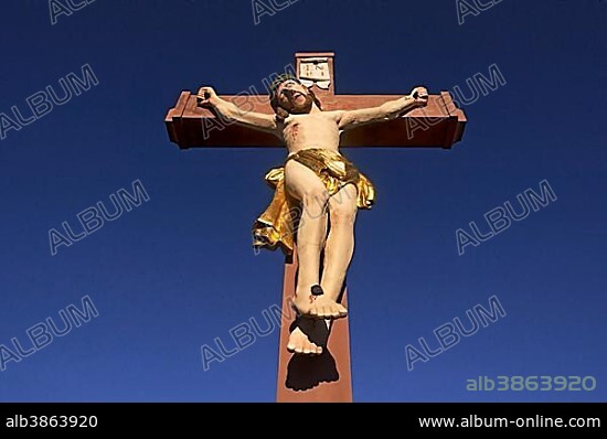 Colored stone crucifix, against a blue sky, Ringsheim, Baden-Württemberg, Germany, Europe.