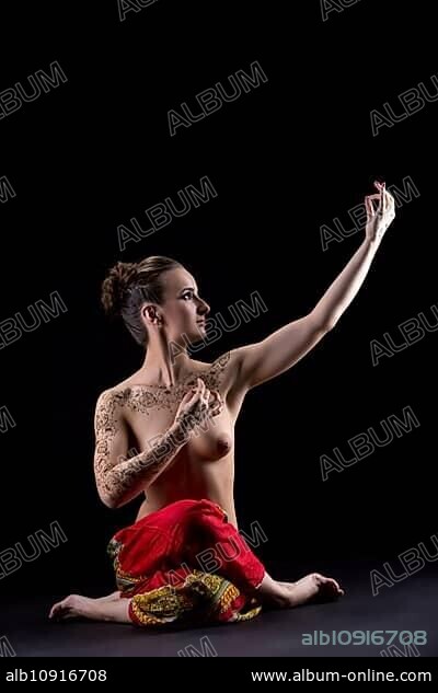 Attractive topless woman practicing yoga at camera.