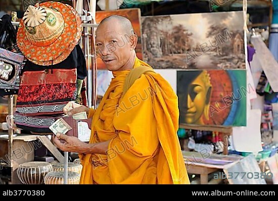 Buddhist monk buying statues of saints from a souvenir shop on the grounds of Angkor Wat, Cambodia, South East Asia, Asia.