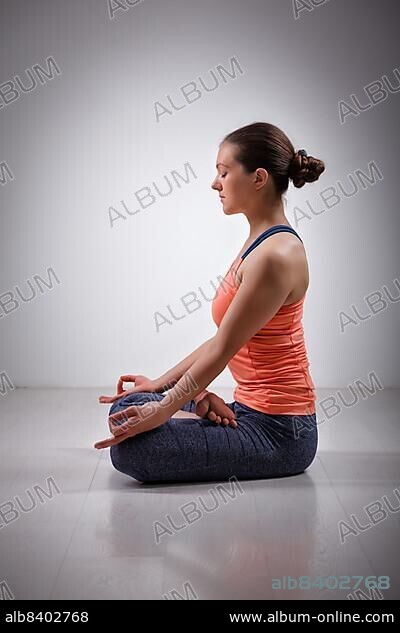 Beautiful fit yogini woman meditating in yoga asana Padmasana (Lotus pose) cross legged position for meditation with Chin Mudra, psychic gesture of consciousness.