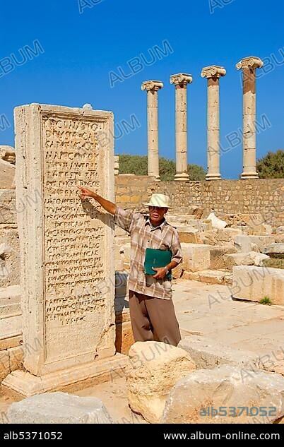 Local guide translates inscription on stone plate old forum Leptis Magna Libya.