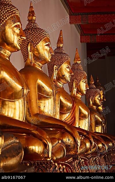 Row of golded sitting Buddha statues in Buddhist temple Wat Pho, Bangkok, Thailand. Low point of view, focus on 3rd one from the left.