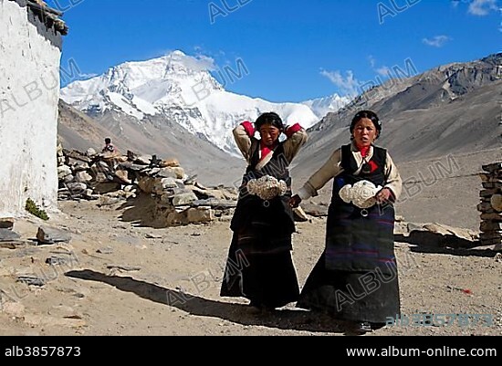 Two Tibetan pilgrims women in front of Mt. Everest Chomolungma Rongbuk Monastery Tibet China.