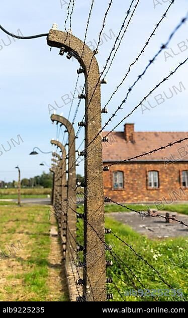 Auschwitz, Poland - 15 September, 2021: barbed wire fence and lanterns with guard house in the background at the Auschwitz concentration camp.