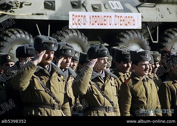 Russian soldiers saluting in front of a train transporting armoured vehicles during the withdrawal of Soviet troops from Stendal, East Germany/GDR, Europe.