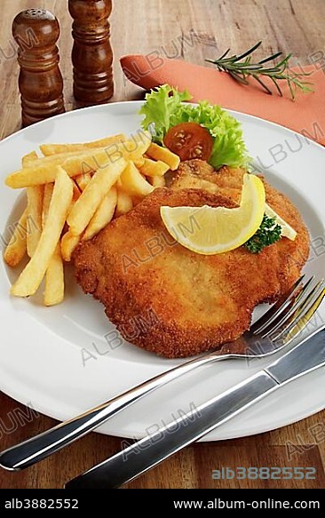 Breaded pork escalope Viennese style with lemon slice and French fries.