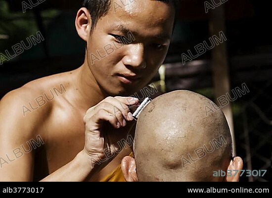 Young Buddhist monk having his head shaved with an old fashioned safety razor in Chiang Mai, Thailand, Asia.