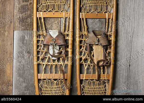 Antique snowshoes on rustic cabin wall.