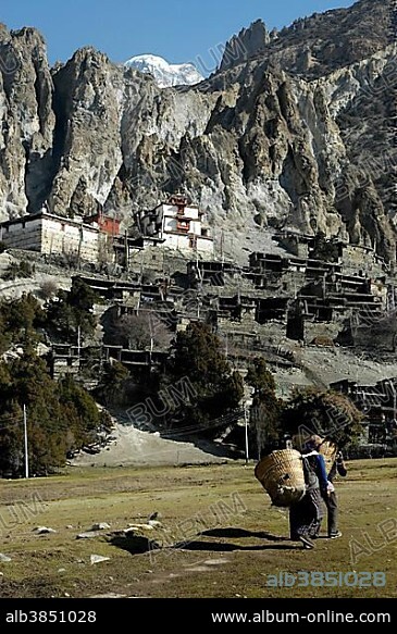 Nested village below rocks and old Braga Gompa Annapurna Region Nepal.