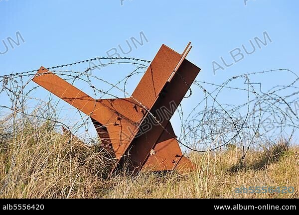 Barbed wire and Czech hedgehog static anti-tank defences from the Second World War on a beach in Normandy along the Atlantic Wall, France, Europe.