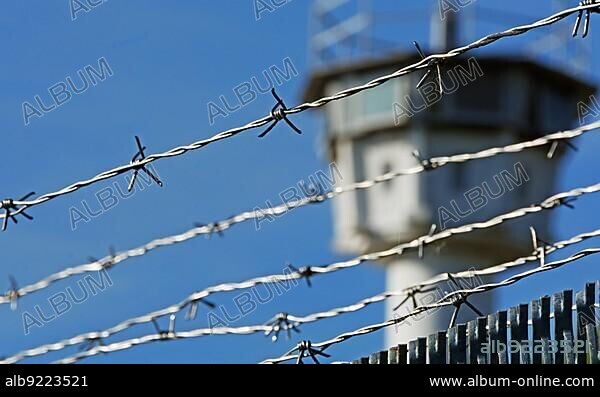 Stacheldraht mit Wachturm im Hintergrund. Barbed wire with a watchtower in the background.