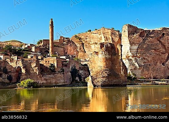 Remains of medieval Artukid, old Tigris bridge, built in 1116 by Artukid Fahrettin Karaaslan, with the old town Hasankeyf and its ruins on the cliffs abover the river Tigris and the minaret of the El Rizk Mosque, built in 1409, Turkey, Asia.