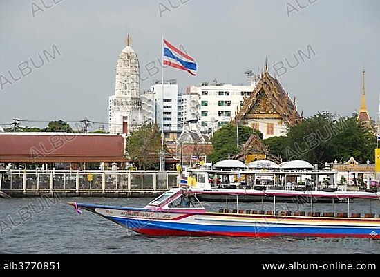 Boat on the Mae Nam Chao Phraya River, Thai national flag, in the back a Buddhist temple, Bangkok, Thailand, Southeast Asia, Asia.