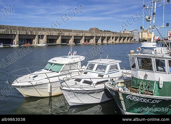 Fishing boat and the German WW2 Kriegsmarine submarine base, fortified U-boat pen in the port of Saint-Nazaire, Loire-Atlantique, France, Europe.