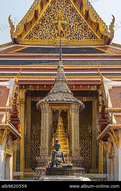 The famous Buddhist temple Wat Phra Kaew; located in the The Grand Palace in the historic centre Bangkok. In the foreground; the statue of the Seated Hermit; behind; the statue Phra Phothi That Phima.