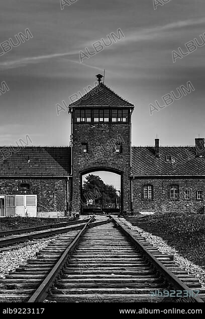 Auschwitz, Poland - 15 September, 2021: black and white view of the gatehouse and train tracks at Auschwitz Concentration Camp in Poland.